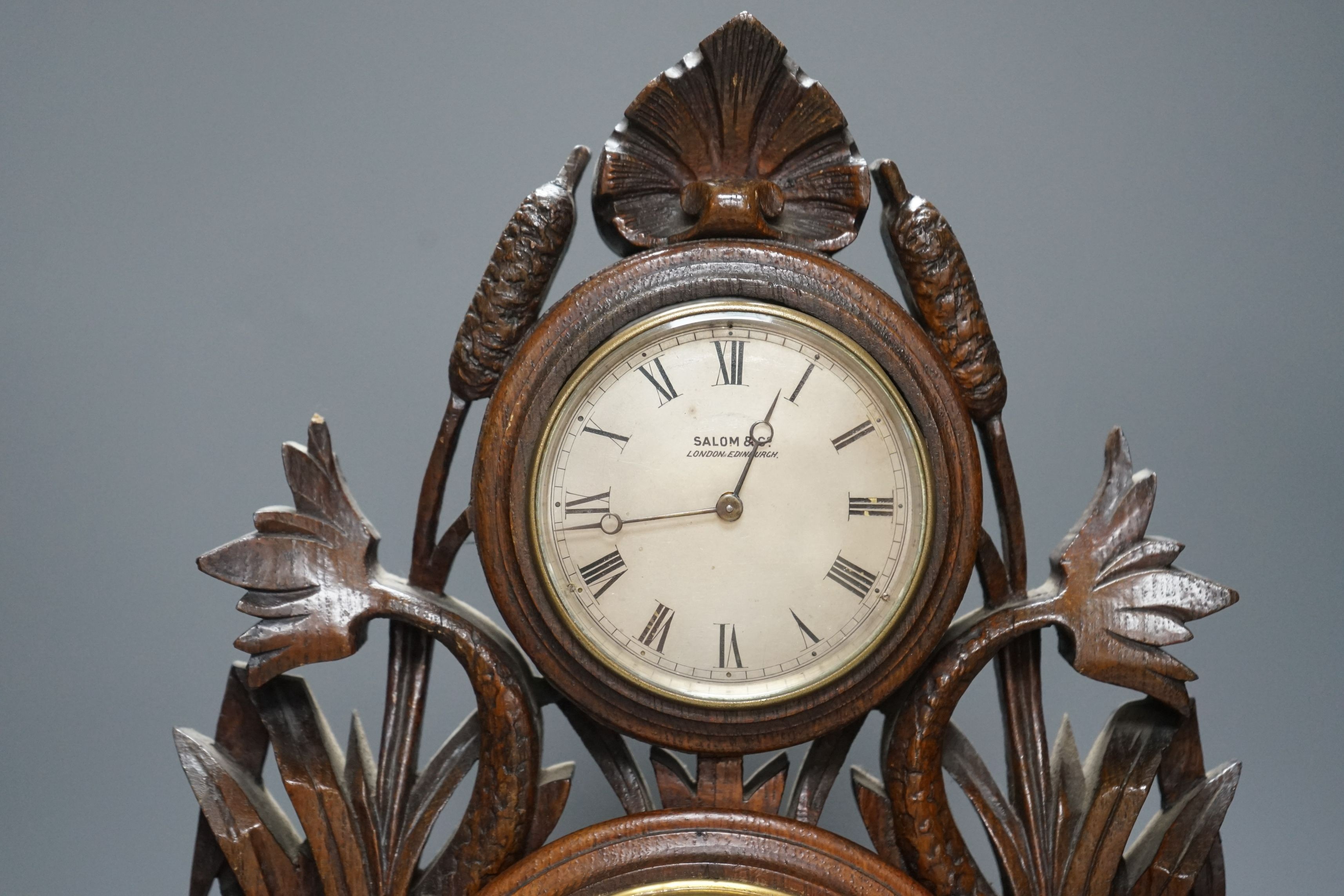 A Victorian oak timepiece combined barometer by Salom & Co., carved with stylised fish and bull rushes, height 46cm